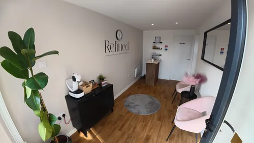 Pink chairs, a mirror and the Refined wall sign inside the clinic.